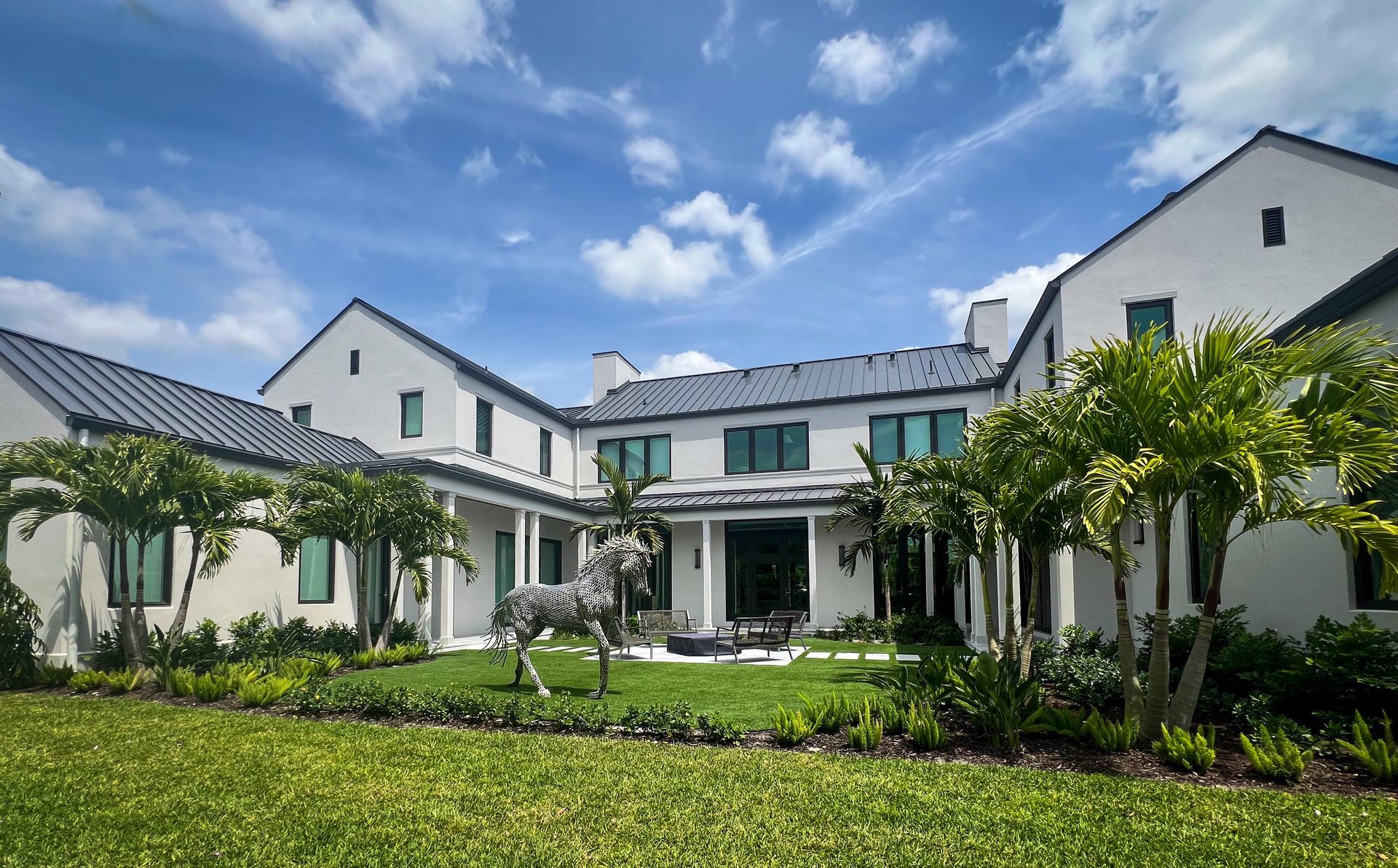 Wellington home with fire pit, outdoor seating, artificial turf, pavers, and palm trees.