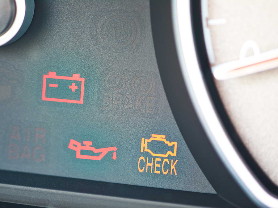 Car dashboard with glowing red battery and oil pressure warning lights and an orange check engine light.