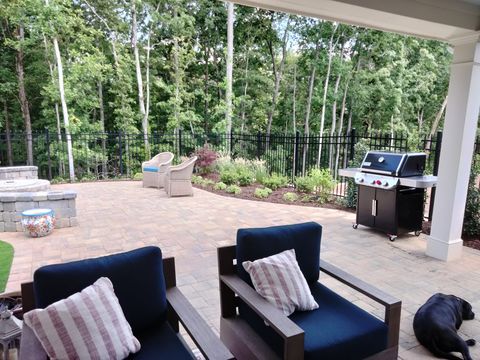 A dog is standing on a patio with chairs and a grill.