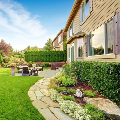 A large house with a lush green lawn and a stone walkway leading to it.