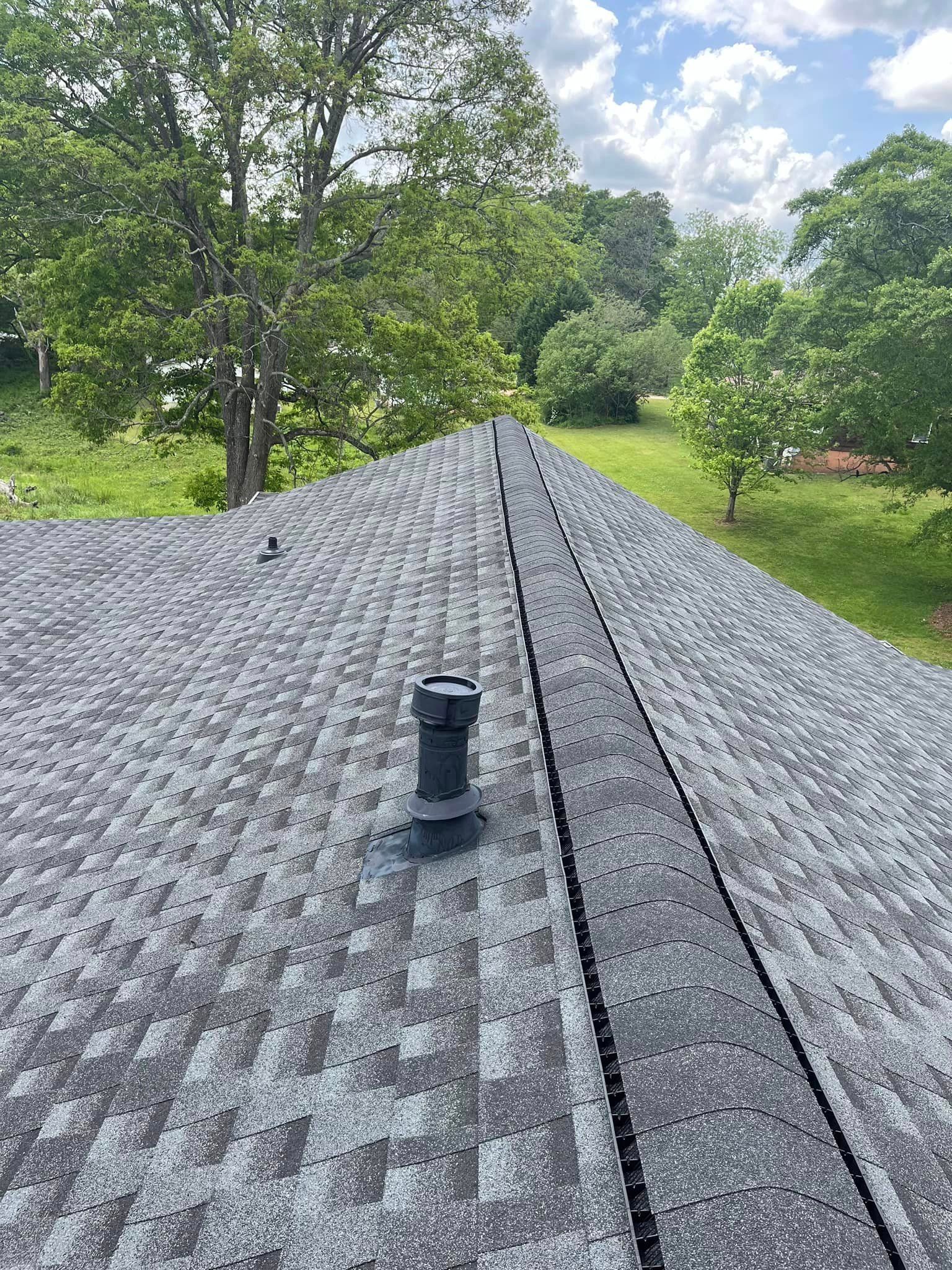 A roof with a chimney on it and trees in the background.