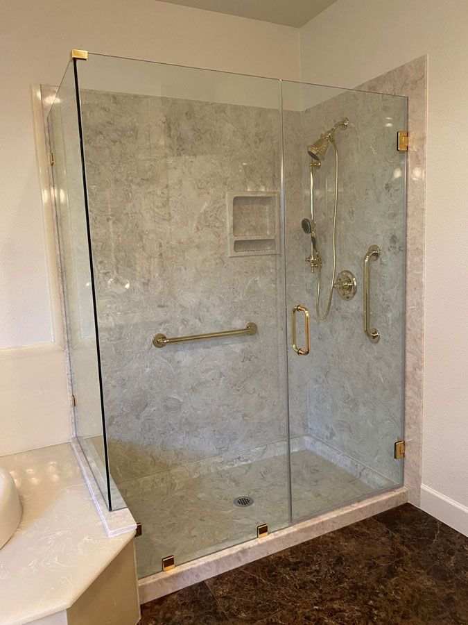 Glass-enclosed walk-in shower with marble walls, chrome fixtures, and grab bar in a bathroom