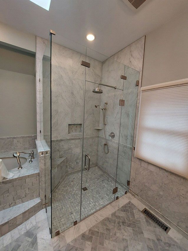 Modern tiled bathroom with glass shower enclosure, bench, and frosted window shades