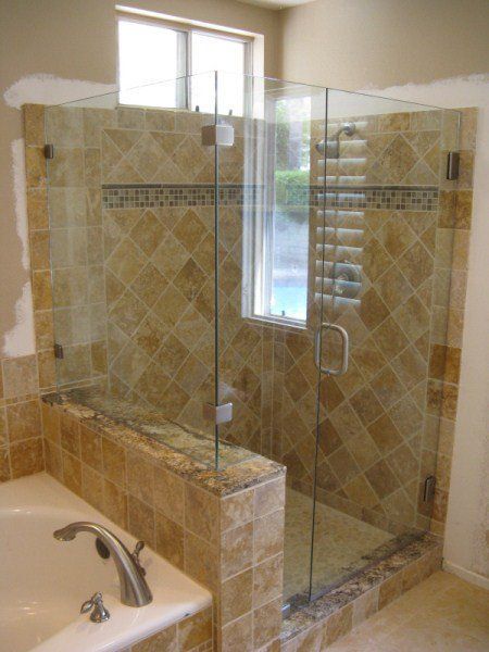 Walk-in glass shower with beige tile and a built-in bench beside a bathroom sink