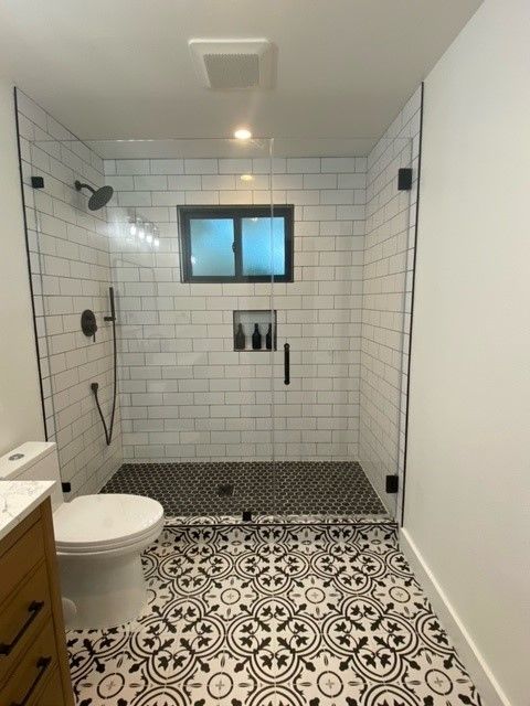 Modern tiled bathroom with walk-in shower and patterned black-and-white floor tiles