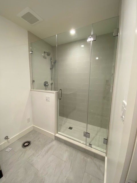 Modern bathroom with a glass-enclosed shower, gray tile floor, and white walls