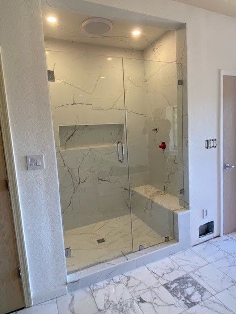 Modern tiled bathroom shower with glass enclosure and marble-look floor and walls