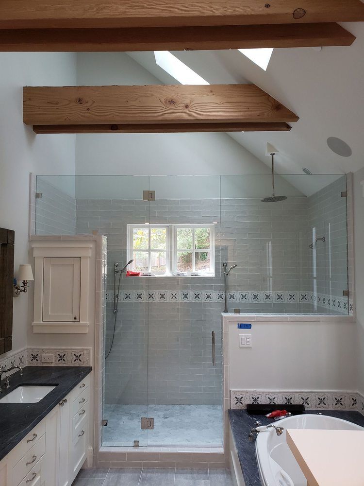 Modern bathroom with glass shower, white vanity, and exposed wooden ceiling beams