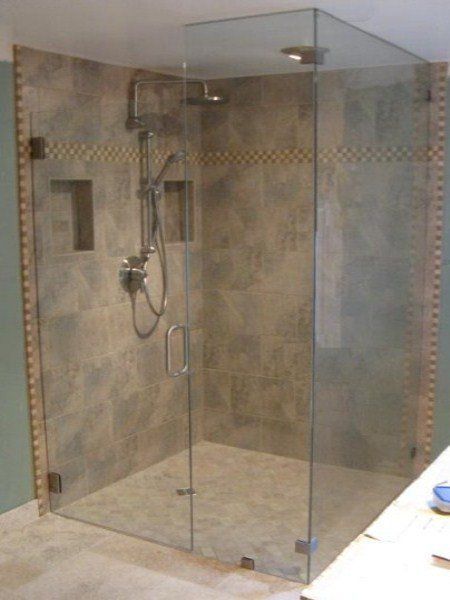 Glass walk-in shower with tiled walls and a handheld showerhead