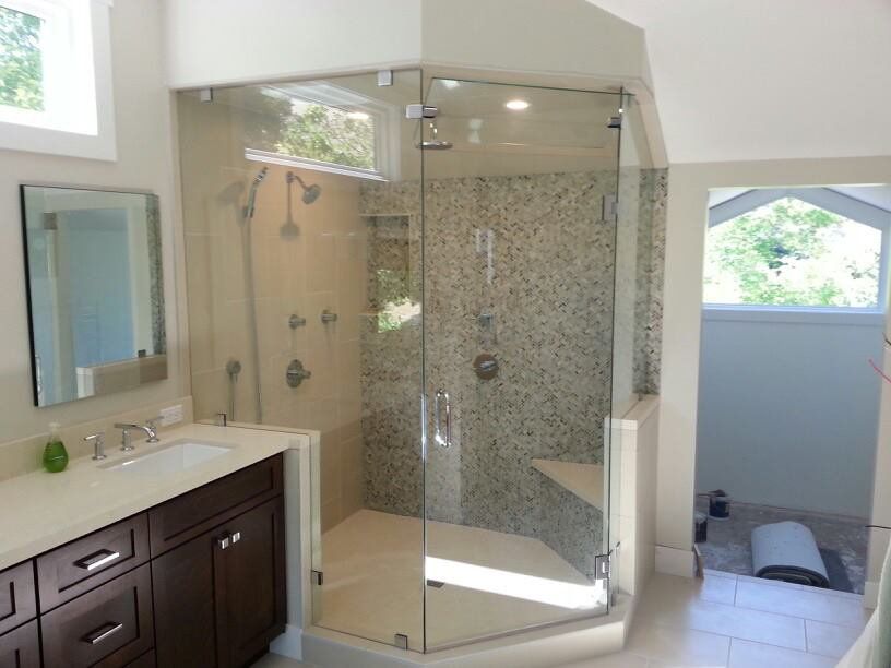 Modern bathroom with glass shower, double vanity, and white tile walls