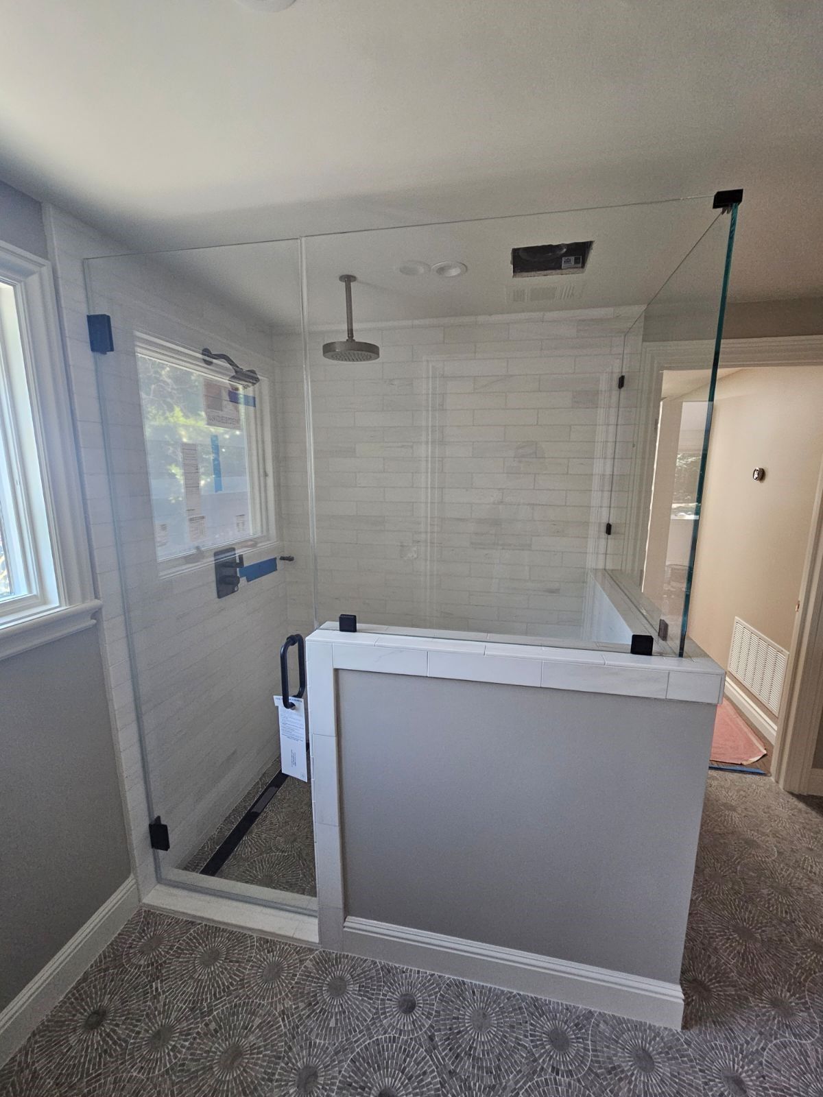 Empty tiled bathroom with a walk-in shower, white half wall, and windowed wall.