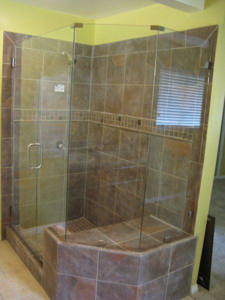 Glass-enclosed tiled shower with a built-in bench in a bathroom