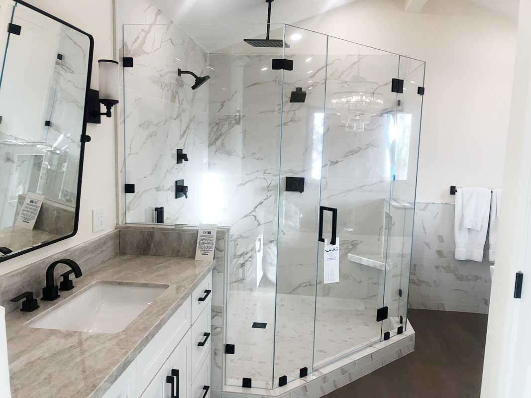 Modern bathroom with glass shower enclosure, marble walls, and a double vanity sink.