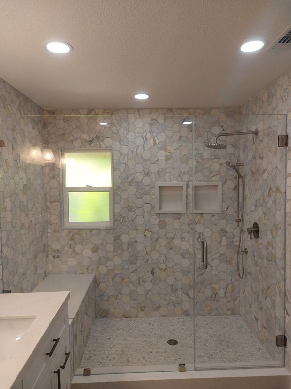 Modern tiled walk-in shower with glass door, built-in niches, and recessed ceiling lights