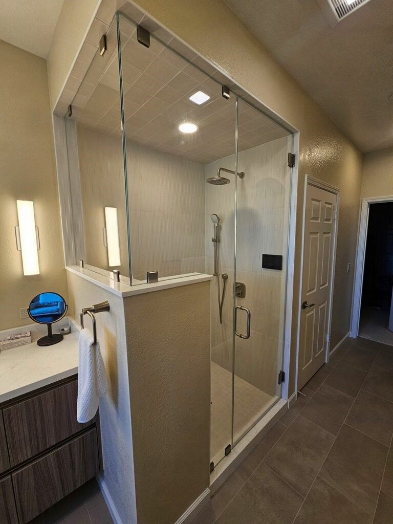 Modern bathroom with glass-enclosed shower, beige tile, and vanity with sink and towel.