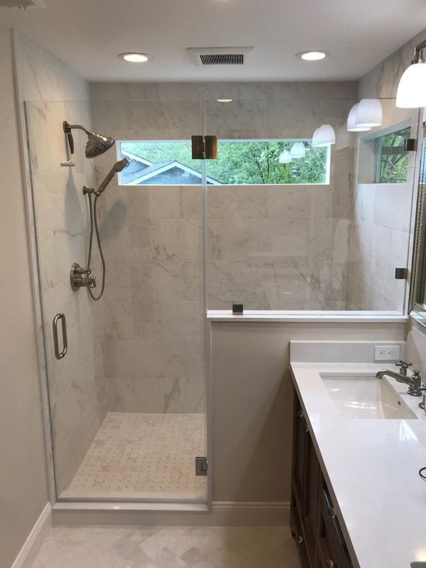 Modern bathroom with a glass walk-in shower and white vanity, viewed from the doorway