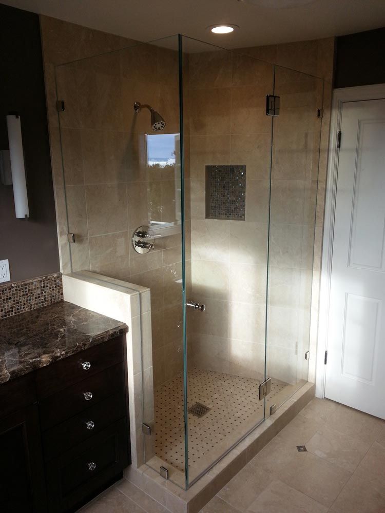 Corner bathroom with glass-enclosed shower, beige tile, granite vanity, and white door.