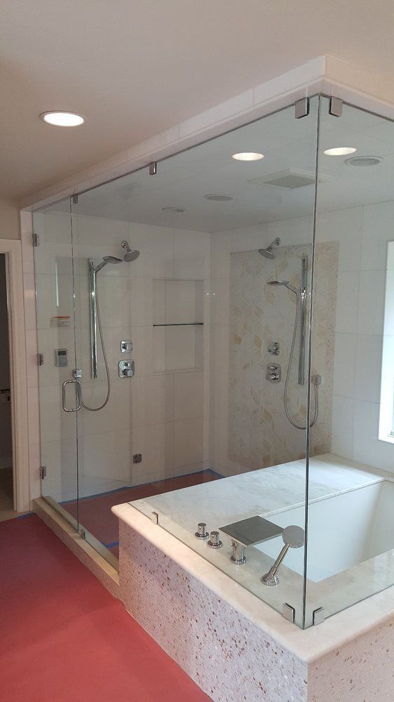 Modern bathroom with glass-enclosed shower and white tiled soaking tub, lit by recessed ceiling lights