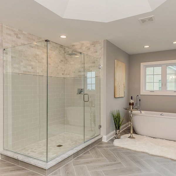 Modern bathroom with glass shower, freestanding tub, gray tile floor, and soft neutral tones