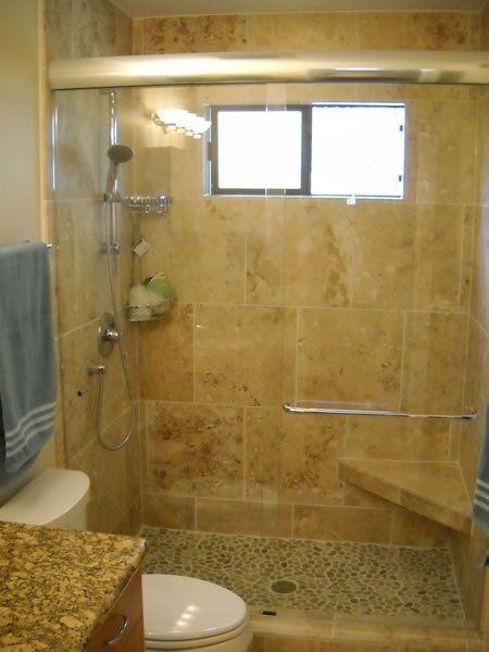 Accessible bathroom with walk-in shower, tan tile, grab bars, bench, and handheld showerhead