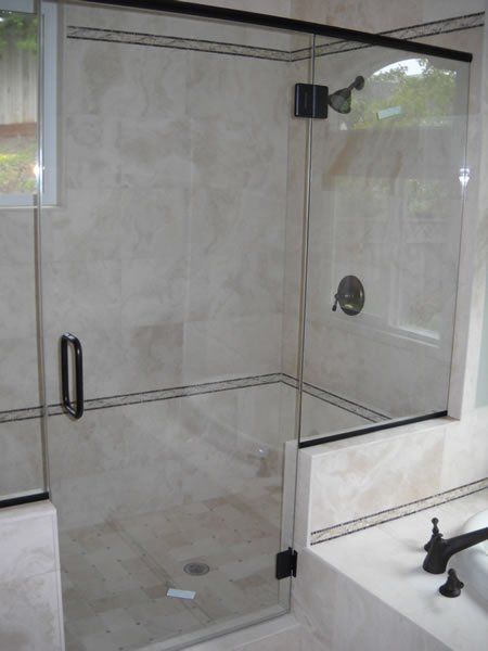 Glass shower enclosure with chrome hardware and beige tiled walls in a bathroom