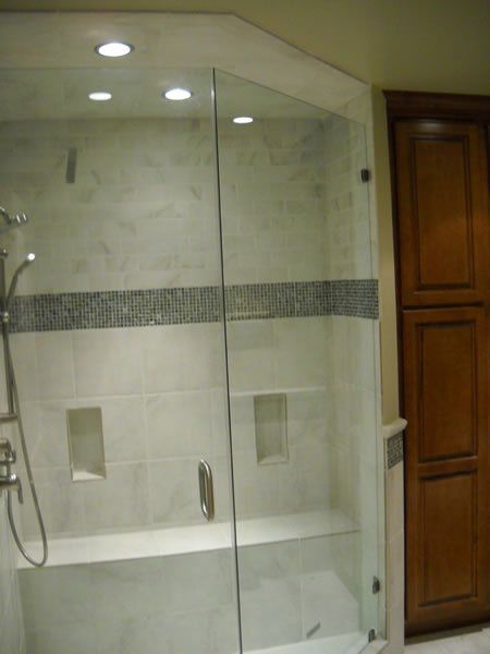 Glass walk-in shower with a white tub and beige tile in a bathroom