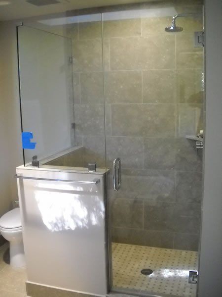 Small bathroom with glass shower enclosure and tiled walk-in shower beside a sink and toilet.