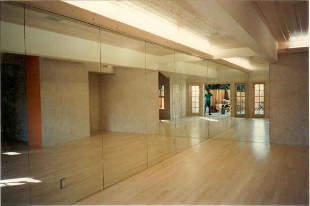 Modern dance studio with mirrored wall, polished wood floor, and overhead lighting