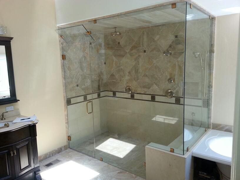 Glass-enclosed walk-in shower with tiled walls and built-in bench in a bright bathroom