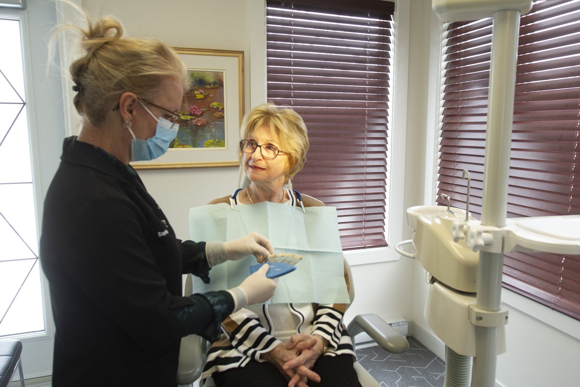 Un dentiste portant un masque et des gants consulte un patient assis dans son cabinet dentaire.