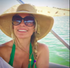 Smiling woman in a sun hat and sunglasses on a boat, with turquoise water behind her