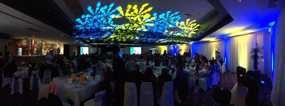 A Large Group of People Are Sitting at Tables in a Large Room — Inspired Audio Visual in Coffs Harbour, NSW