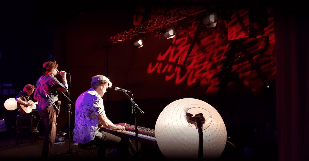 A Man is Playing a Keyboard and Singing Into a Microphone on a Stage — Inspired Audio Visual in Coffs Harbour, NSW