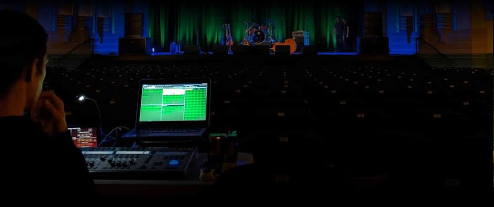 A Man is Sitting in Front of a Laptop Computer in a Dark Room — Inspired Audio Visual in Coffs Harbour, NSW