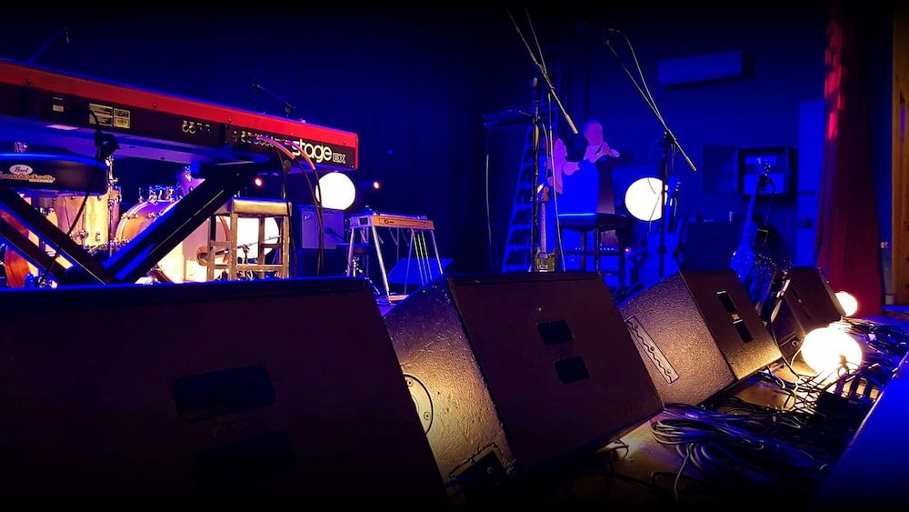 A Row of Speakers Are Sitting on a Stage in a Dark Room — Inspired Audio Visual in Coffs Harbour, NSW