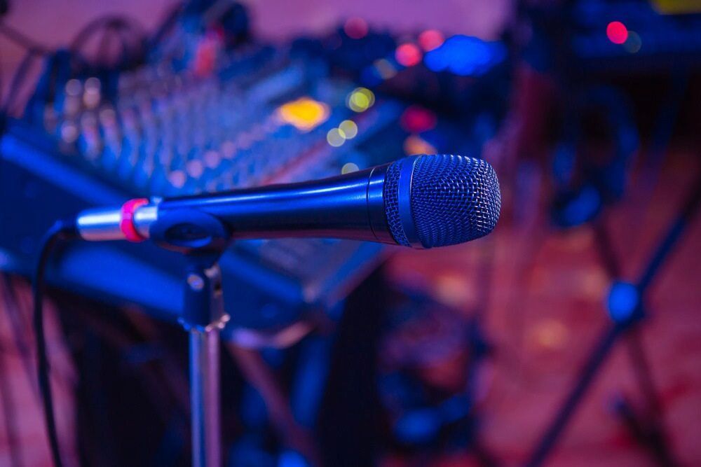 A Microphone is Sitting on a Stand in Front of a Mixer — Inspired Audio Visual in Coffs Harbour, NSW