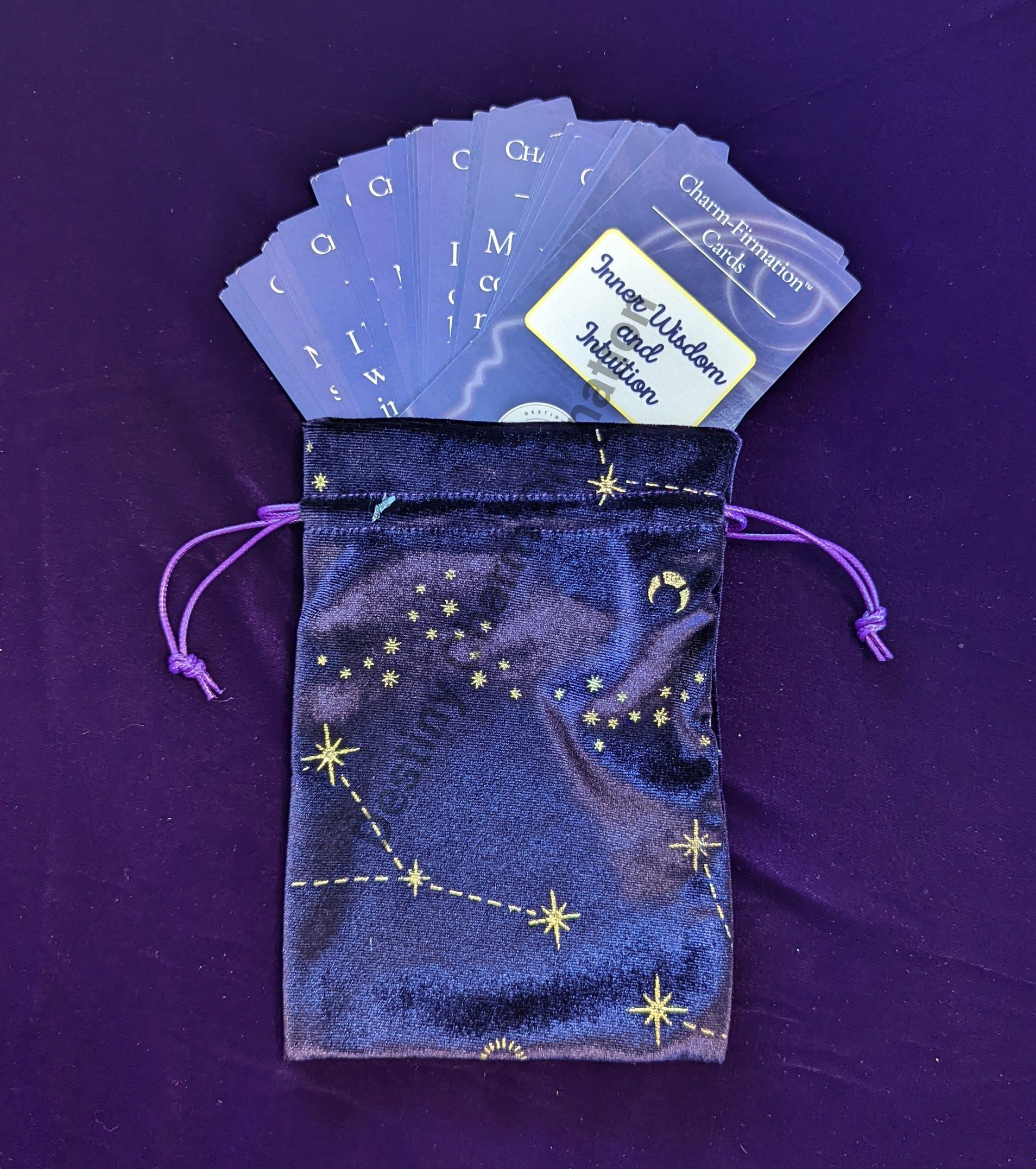 Purple drawstring pouch with starry pattern, holding blue cards and a white label.
