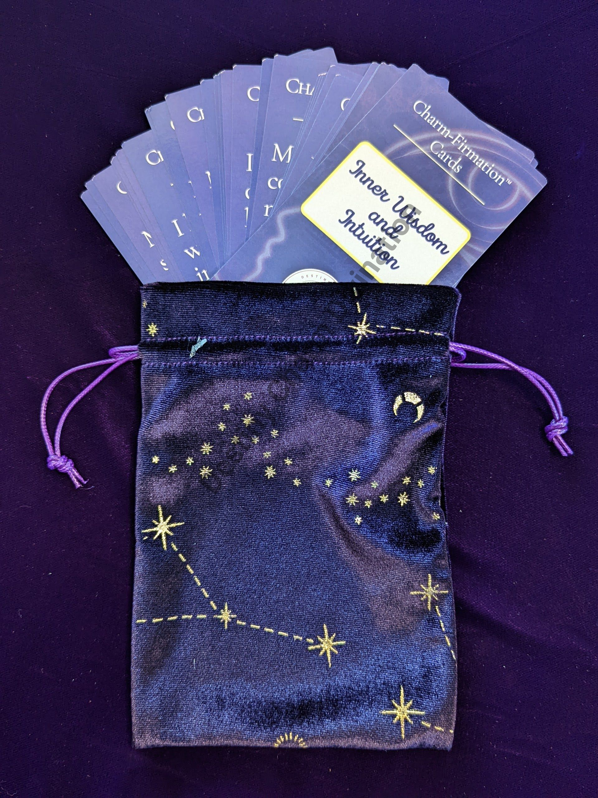 Purple drawstring pouch with starry pattern, holding blue cards and a white label.