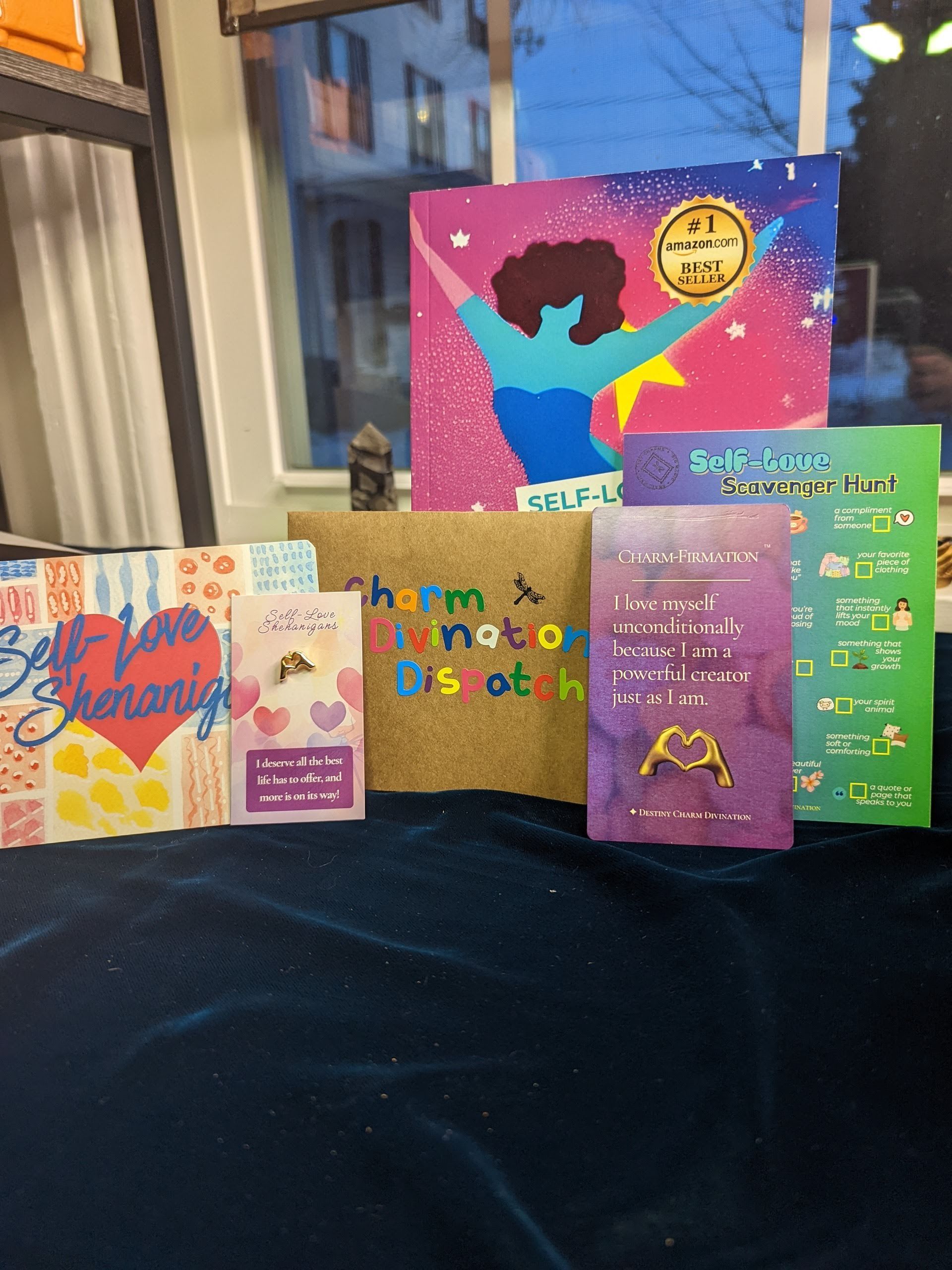 Four colorful greeting cards displayed on a table by a window, including a purple pop-up card and a bright blue silhouette card