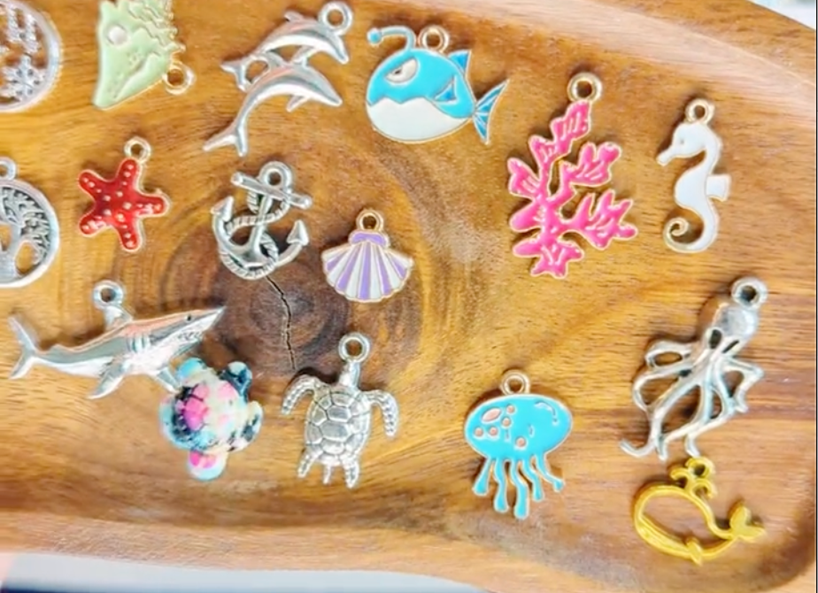 Collection of colorful charms on a wooden tray ocean theme like shark, sea turtle, jellyfish, coral, star fish, and more