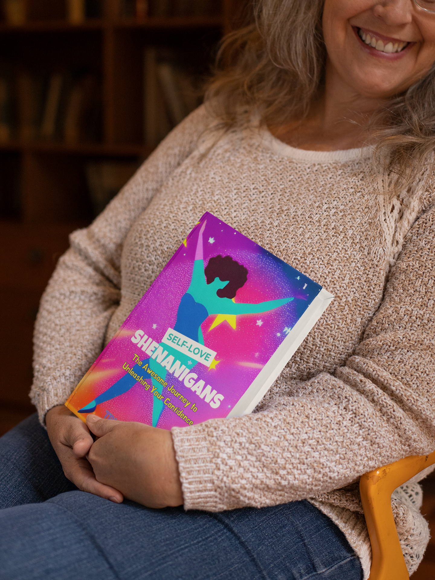 Colorful stack of books with a neon purple “Shenanigans” cover on a pink background