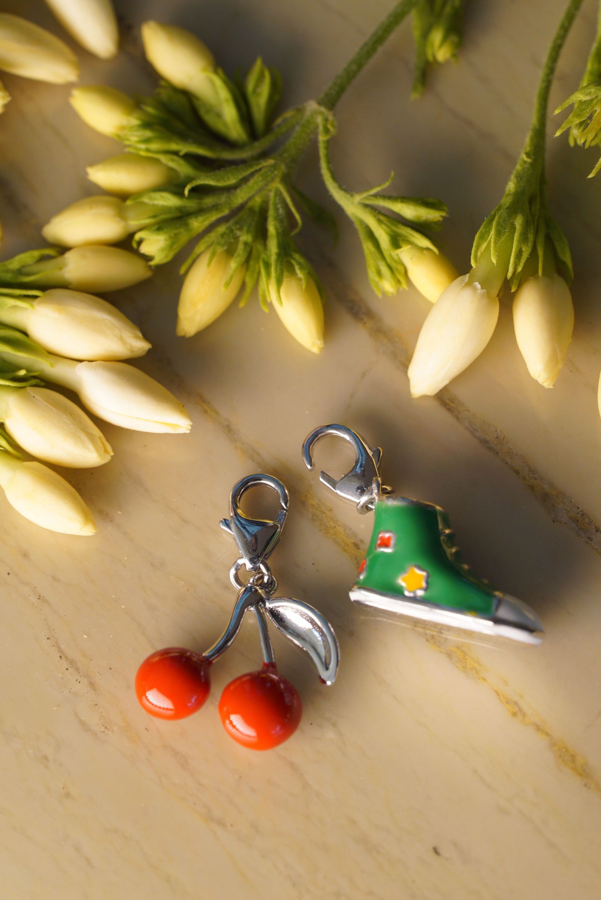 2 charms sit with a cluster of flowers - cherries and a green sneaker