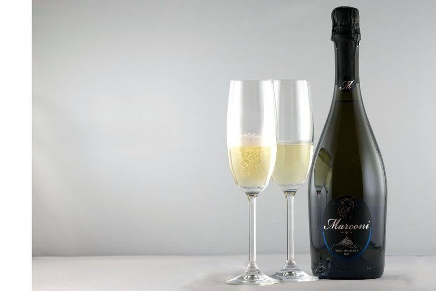 Bottiglia di champagne e due flûte piene su sfondo grigio