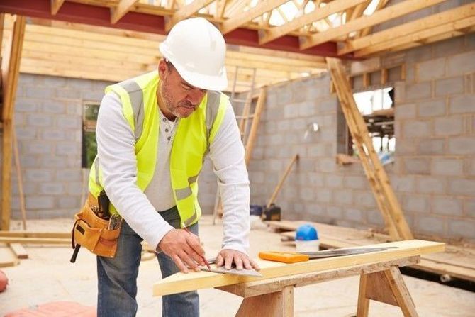 Carpenter measuring wooden beam at job site