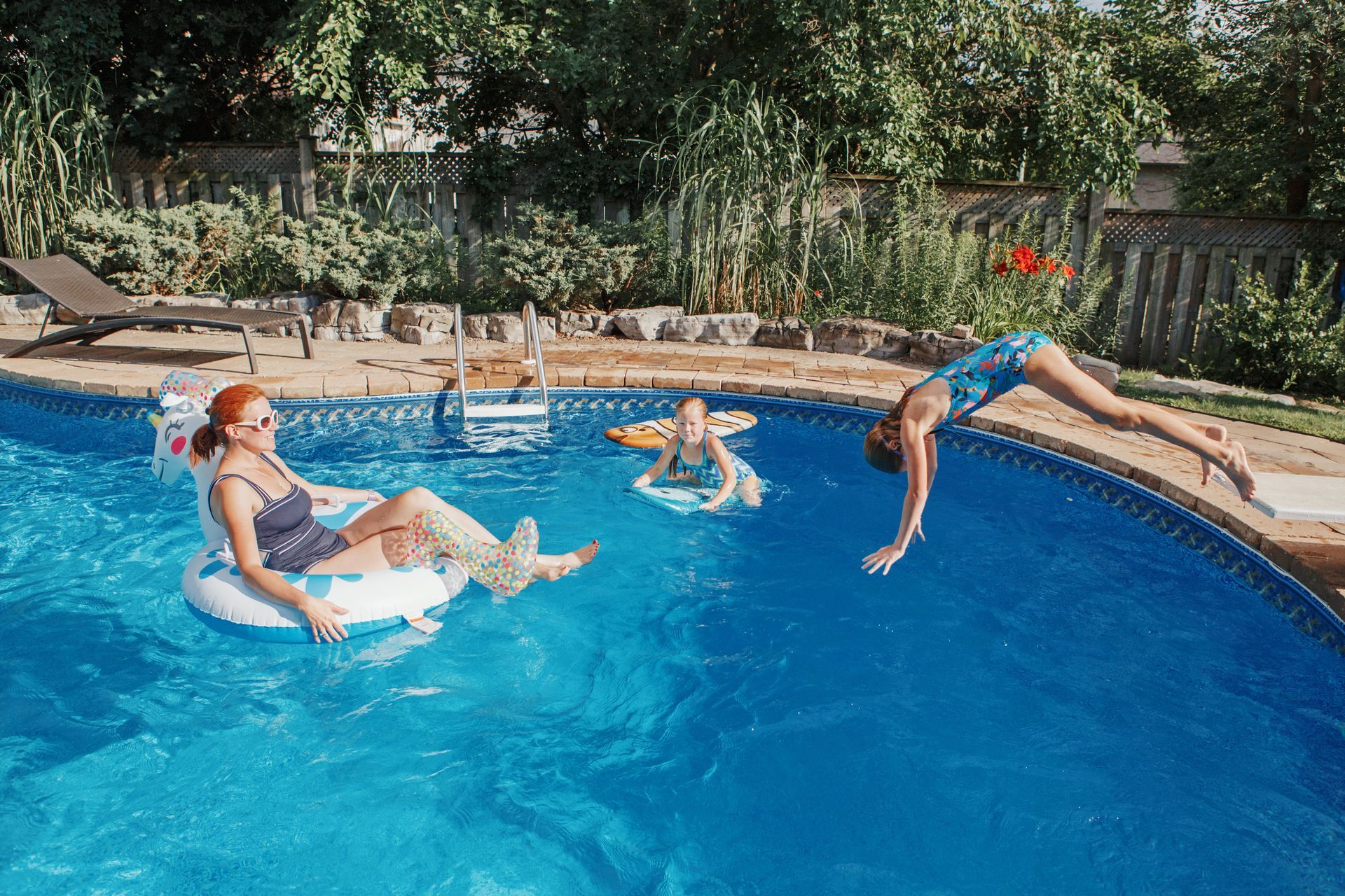 Friends enjoy a backyard pool, floating, diving, and relaxing together. Friends enjoy a backyard pool, floating, diving, and relaxing together.