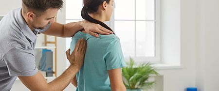 A person receiving a back examination from a healthcare professional in a clinic.