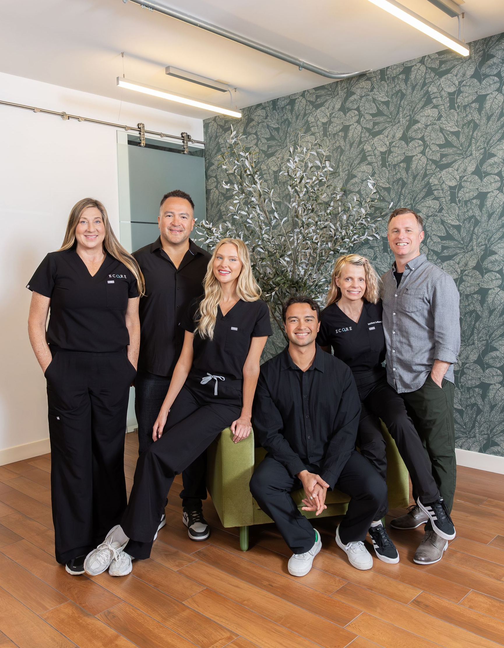 Four healthcare providers posing for a photo in front of a textured wall.