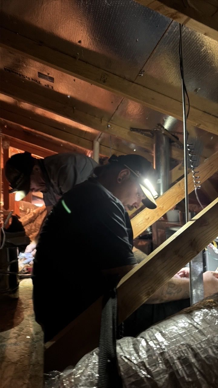 Air-Exx technicians working on ductwork in an attic by headlamp