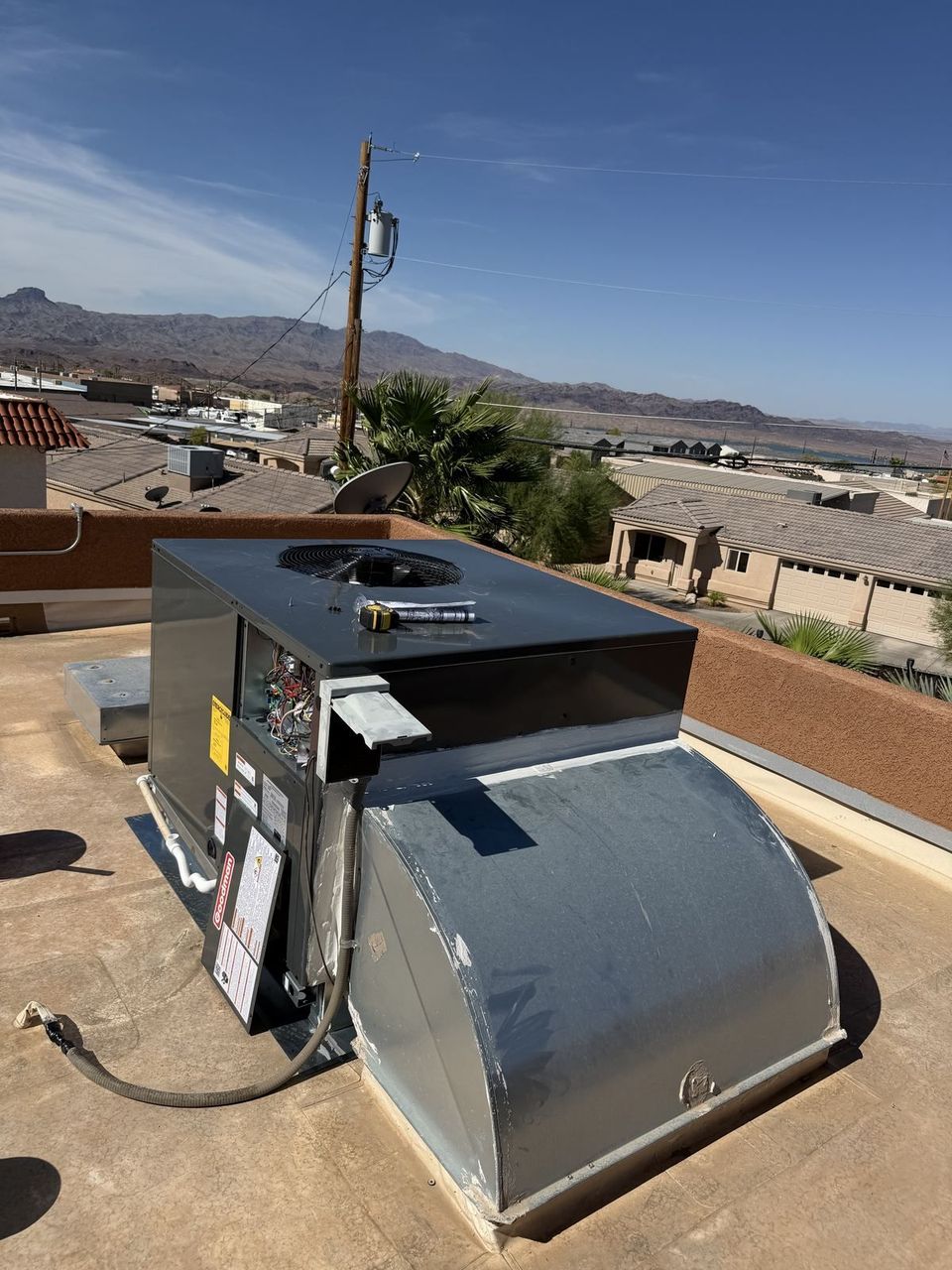 Air-Exx technician servicing a rooftop package unit in the Arizona desert