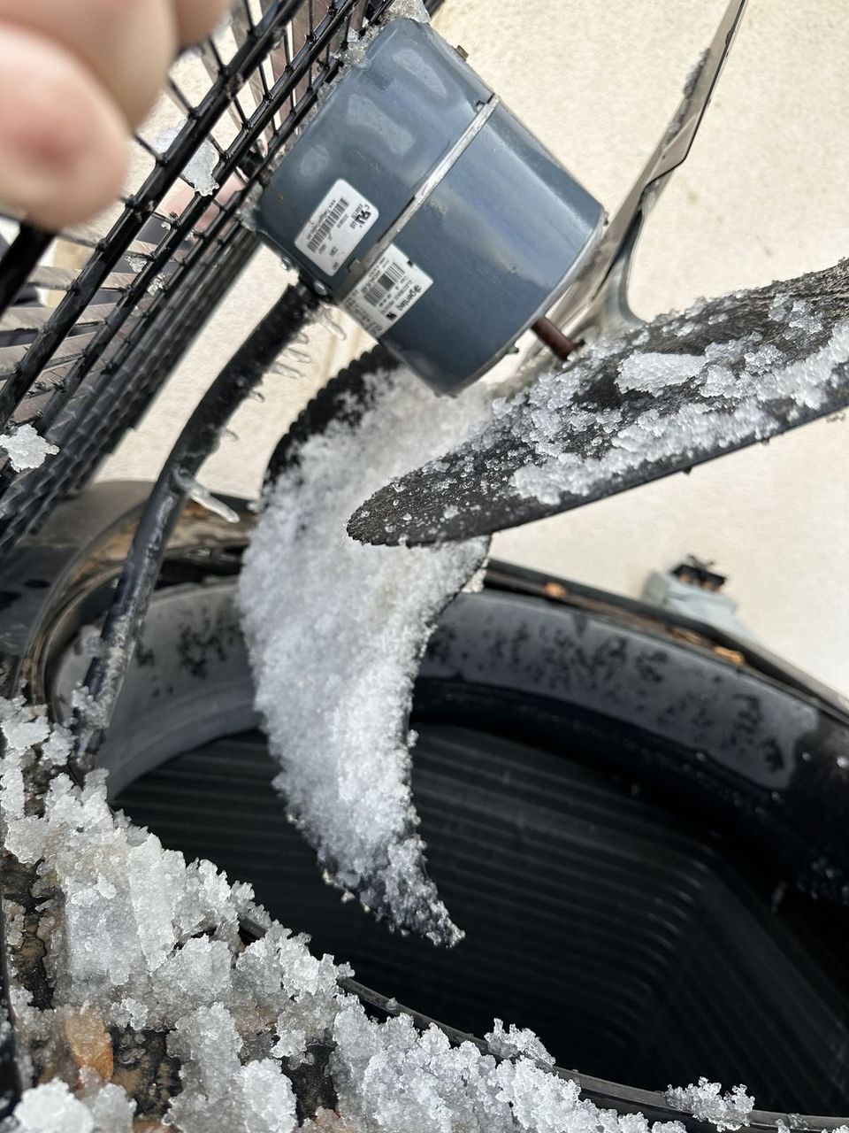 Ice built up on a heat pump fan blade and condenser coil